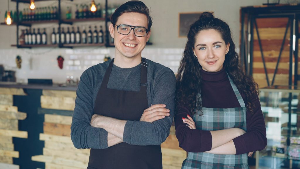 Two cafe owners standing together inside their small business