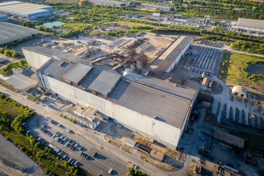 Aerial view of a large industrial facility surrounded by warehouses and car parks