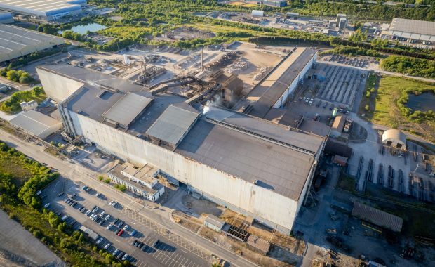 Aerial view of a large industrial facility surrounded by warehouses and car parks